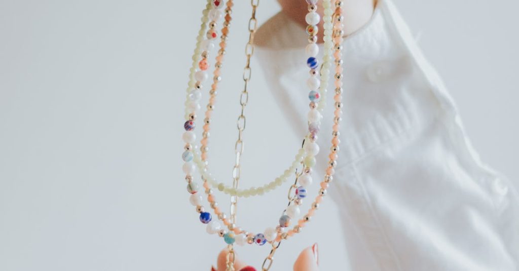 Close-up of hands with red polished nails holding a colorful necklace in a minimalist style.