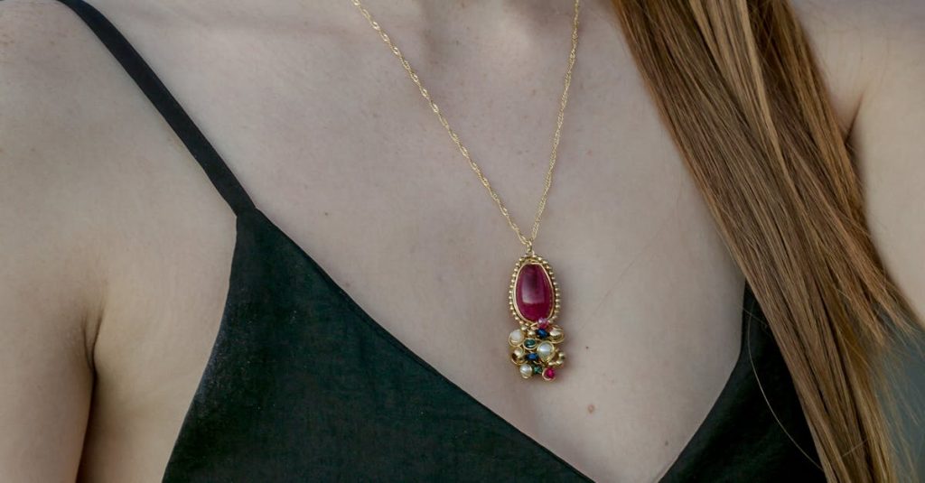 A woman wearing a stylish necklace with a vibrant gemstone pendant, showcasing fashion elegance.